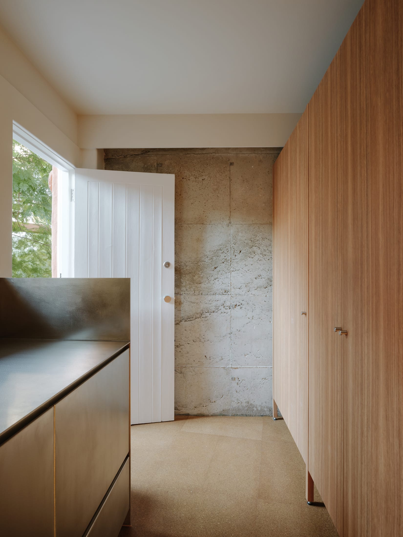 Close-up of cork flooring and an Aalto stool against a white wall.
