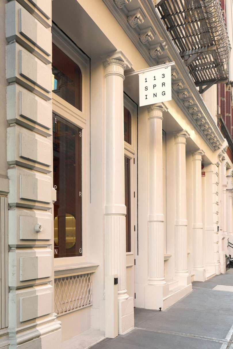 The classic cream-colored facade of 113 Spring Street in SoHo with large windows.