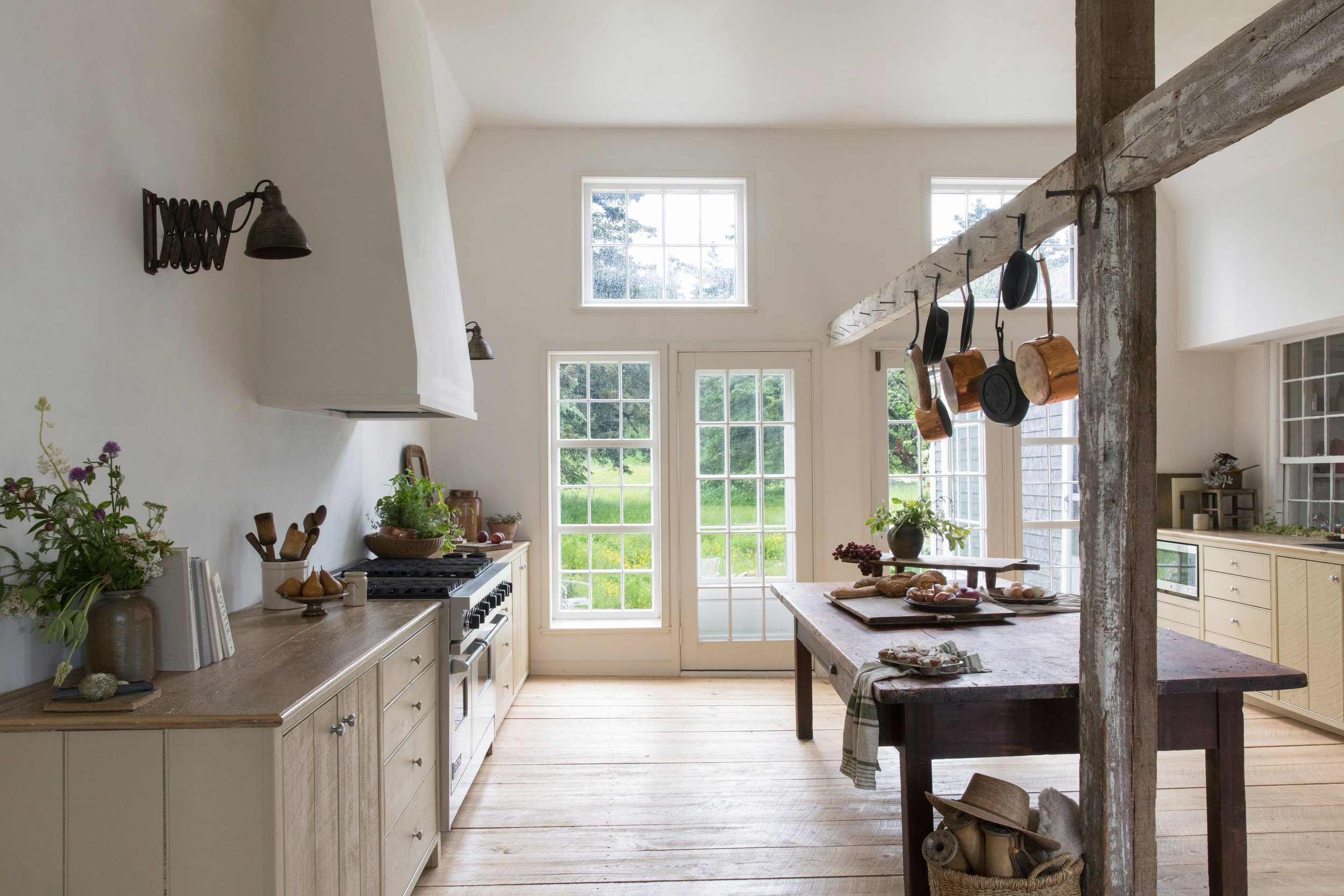 A vintage wooden bakery table used as a kitchen island standing next to an original structural support beam.