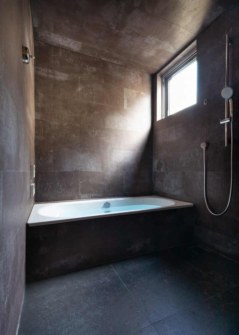 Modern bathroom interior featuring dark moody tiles and clean geometric lines.