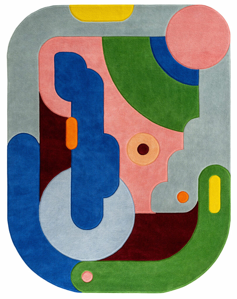 Abstract hand-tufted rug with rounded edges featuring multi-colored geometric shapes by Sam Buckley.