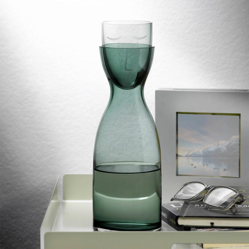 A smoked gray glass carafe with a glass stopper that doubles as a cup.