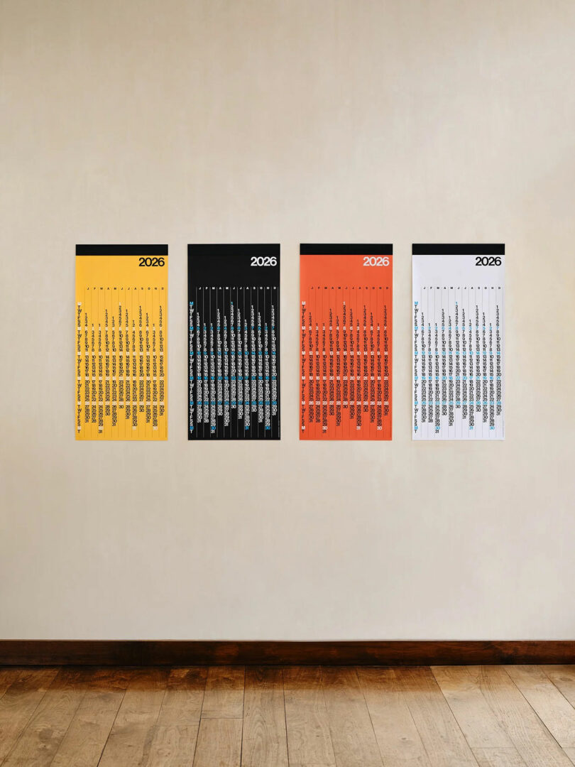 Four minimalist 2026 calendars in yellow, black, orange, and white hanging on a beige wall.