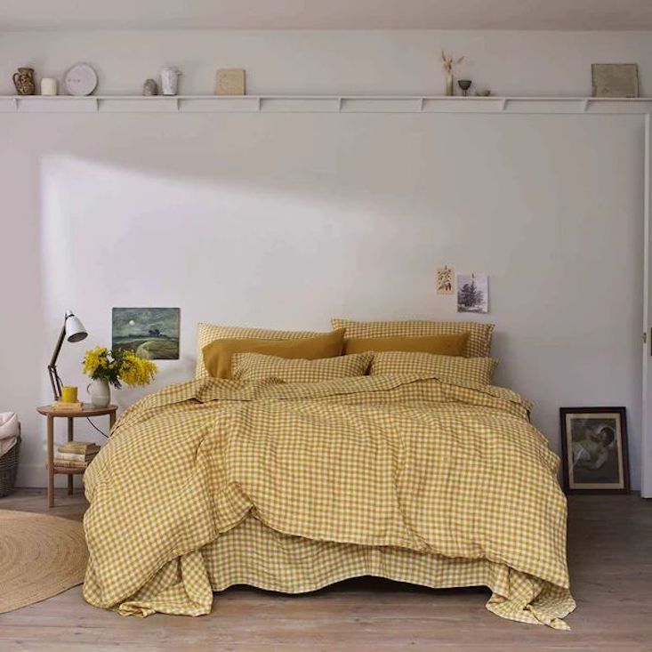 Minimalist bedroom with yellow gingham linen bedding and Scandinavian-style decor.
