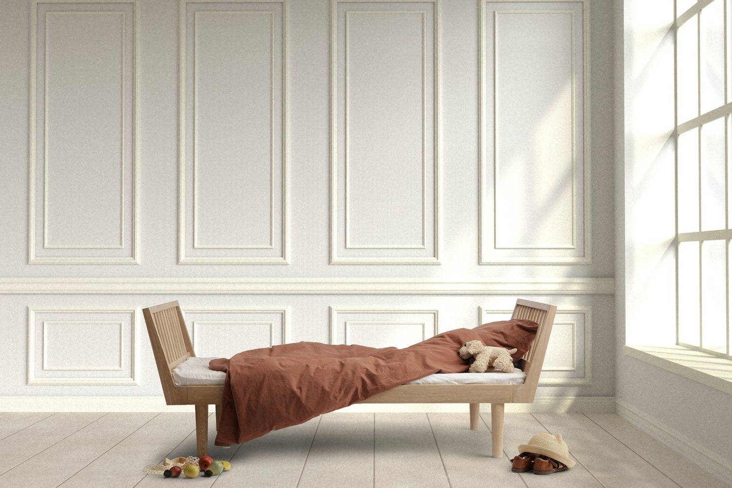A minimalist light wood toddler bed with brown bedding in a bright room.