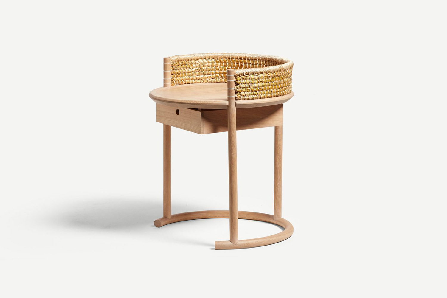Light wood and rattan circular nightstand styled in a bright, minimalist bedroom setting.