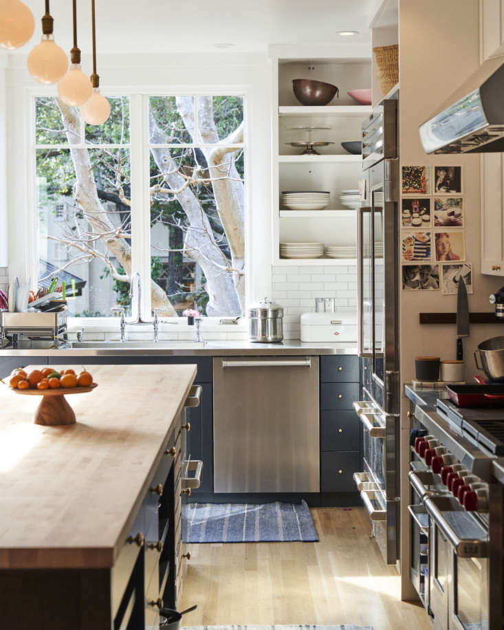 Close-up of a stainless steel countertop with an integrated sink and a large maple butcher block island.