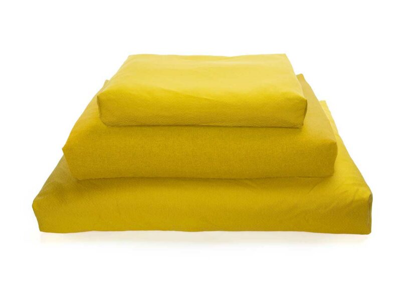 A stack of three rectangular Oksa dog beds in different muted color tones.