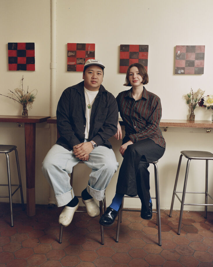 Anthony Ha and Sadie Mae Burns standing inside their restaurant featuring terracotta floors and cherry wood furniture.