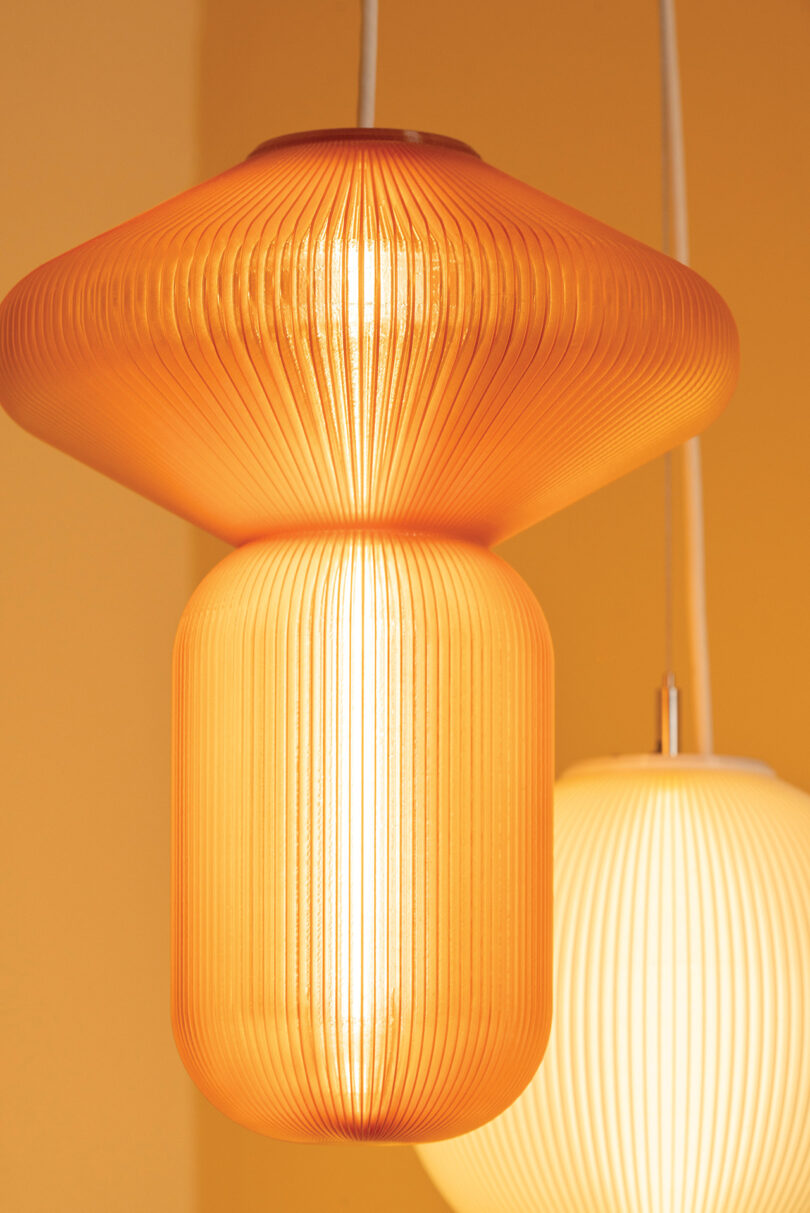 Orange and white translucent ribbed pendant lights illuminating a warm-toned room.