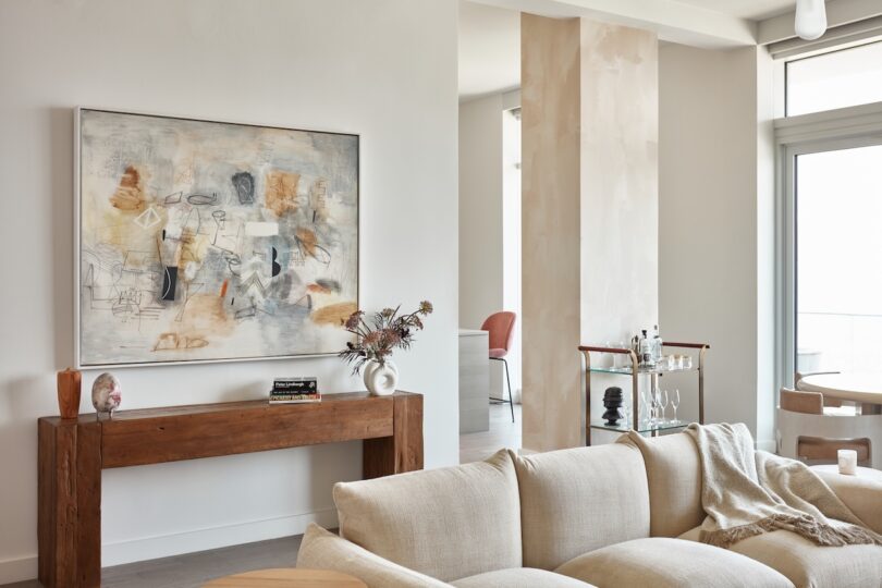 A modern living area featuring a solid wood console table and a plush beige sofa with high-quality textile upholstery.