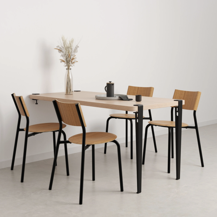 Wall-mounted wooden dining table with black legs and matching minimalist chairs.