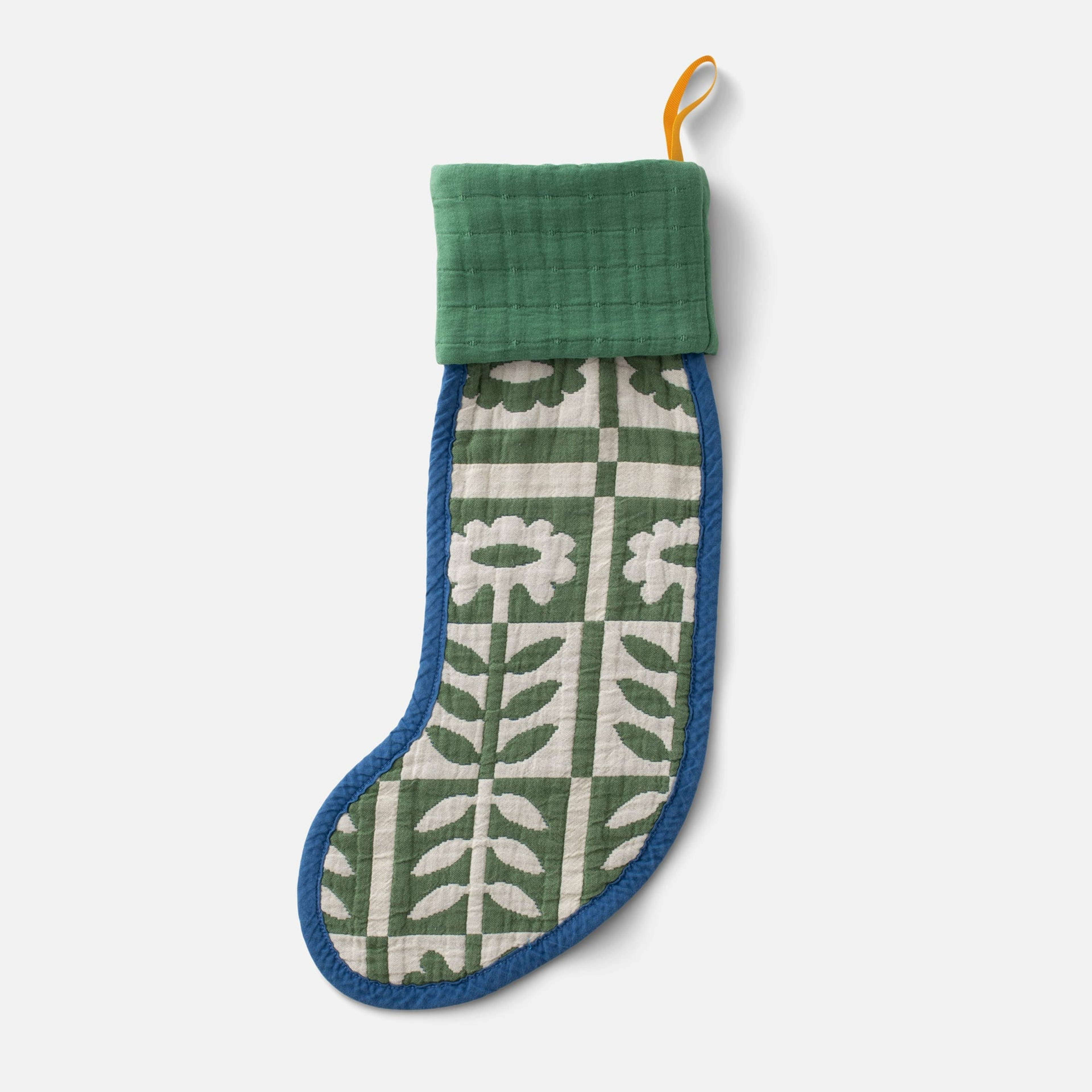 A quilted floral pattern stocking with a linen cuff hanging from a wooden peg.