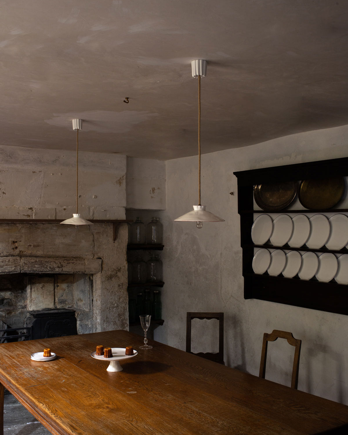 Rustic farmhouse kitchen with stone walls and vintage-style pendant lighting over a dining area.