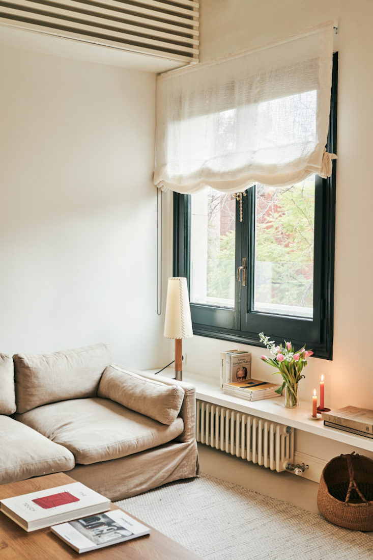 A Básica lamp providing soft light in a snug reading nook with a wooden chair.
