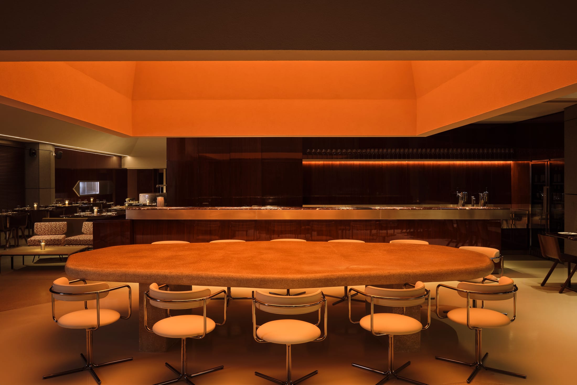 A close-up of a cocktail bar area with deep red flooring and high-gloss wooden walls reflecting warm light.