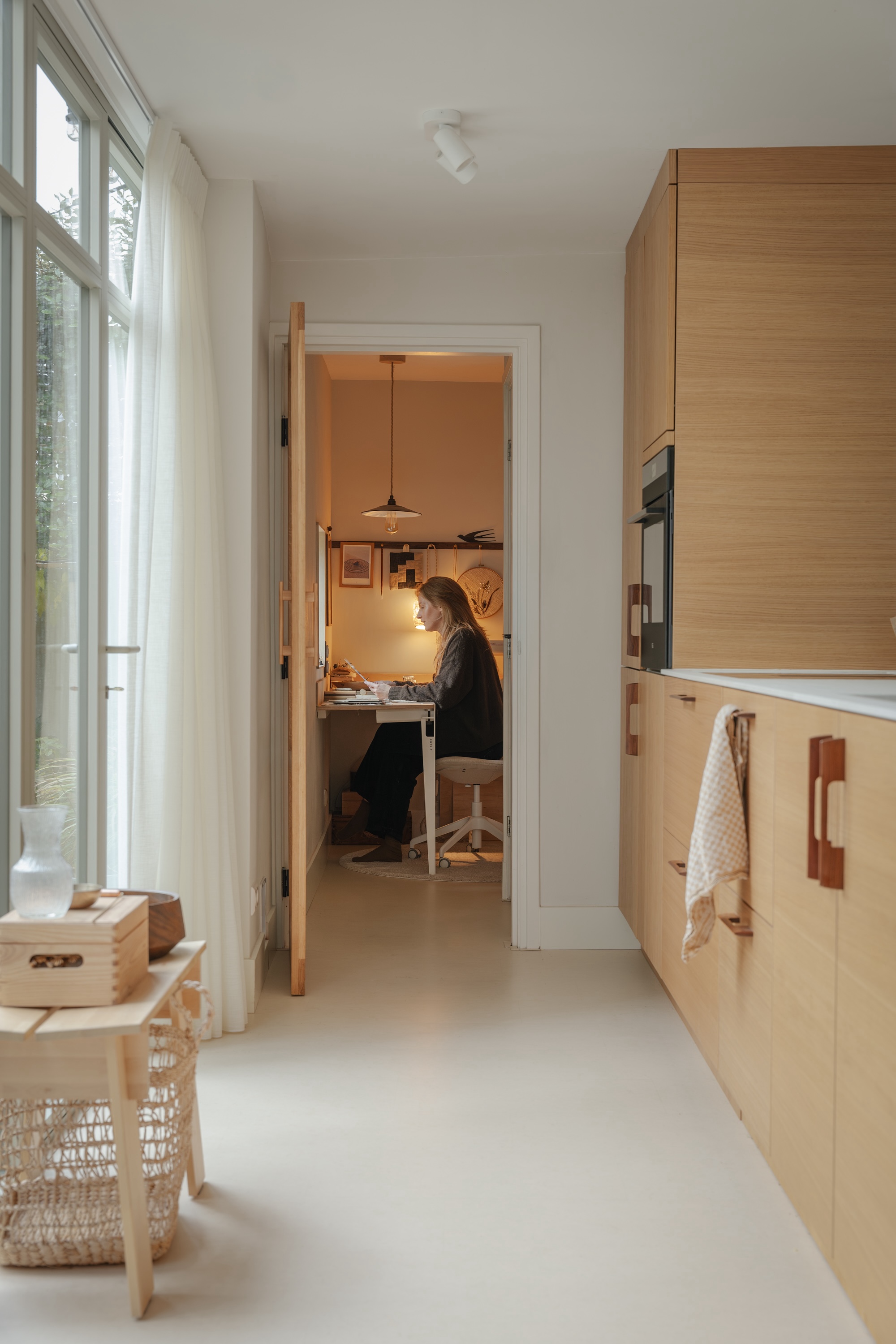 An L-shaped wooden desk with black clamp-on metal legs next to a reeded glass door.
