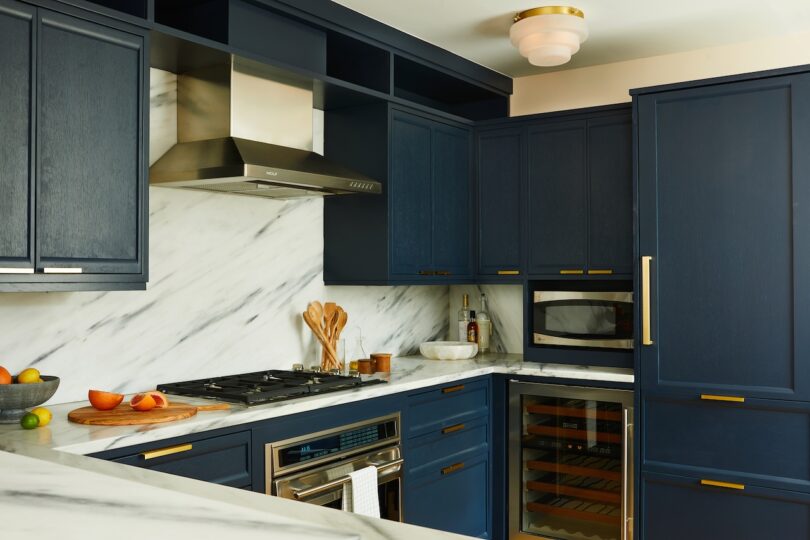 Modern kitchen with Benjamin Moore Hale Navy cabinetry, white marble countertops, and gold hardware.