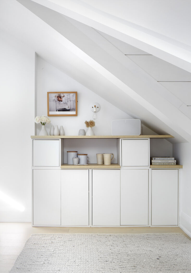 Built-in drawers fitted into a sloped attic wall with an industrial sconce.