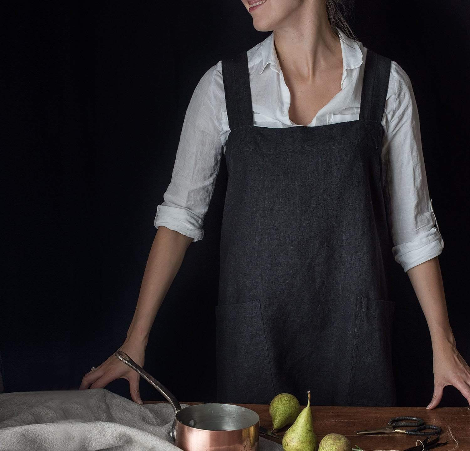 A light-colored linen pinafore apron designed for gardening and light home tasks.