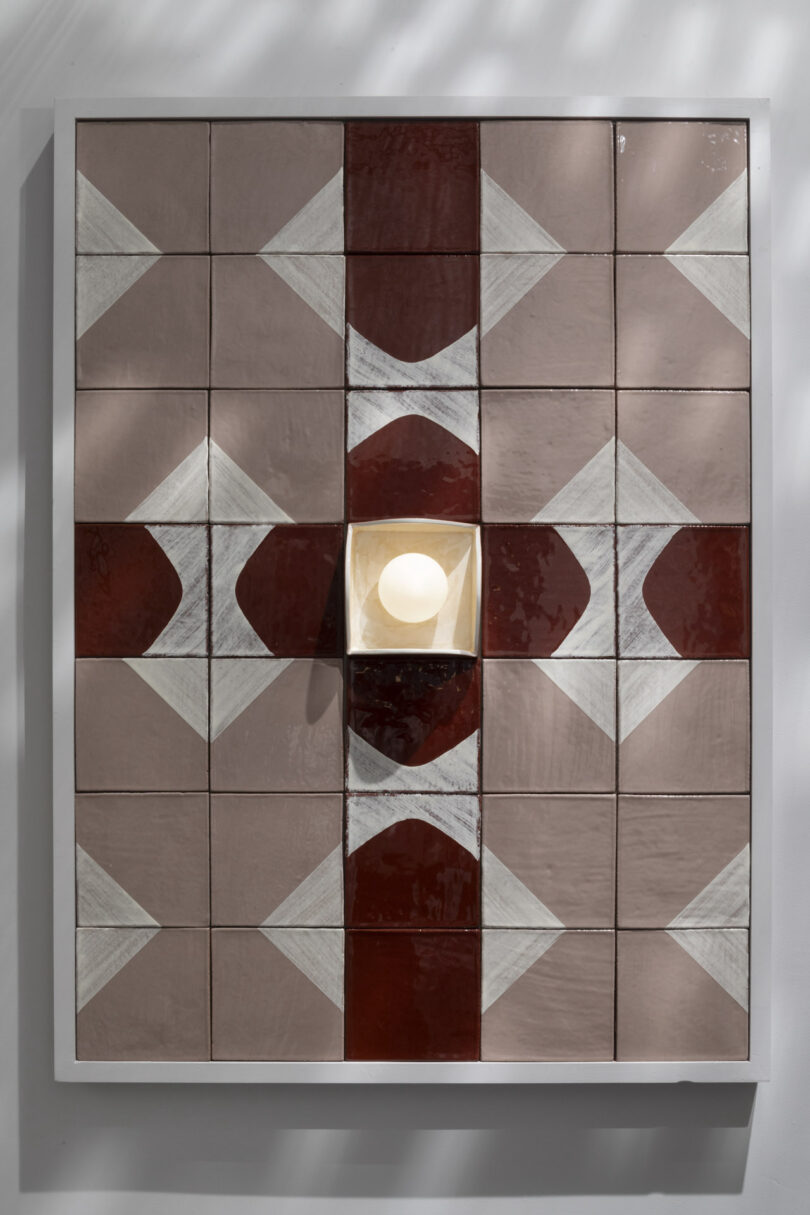 Symmetrical red, white, and pink tile artwork with a central glowing light fixture.