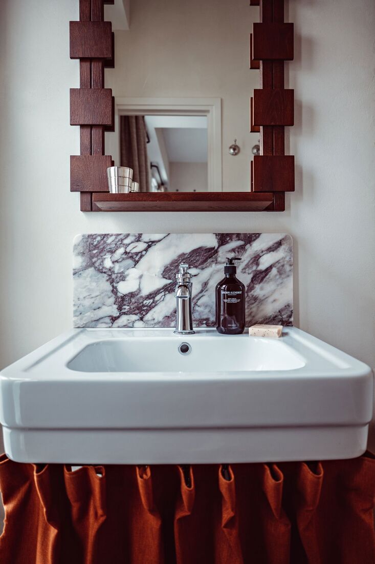 A bold, dark-toned pleated sink skirt in a stylish Parisian hotel bathroom.