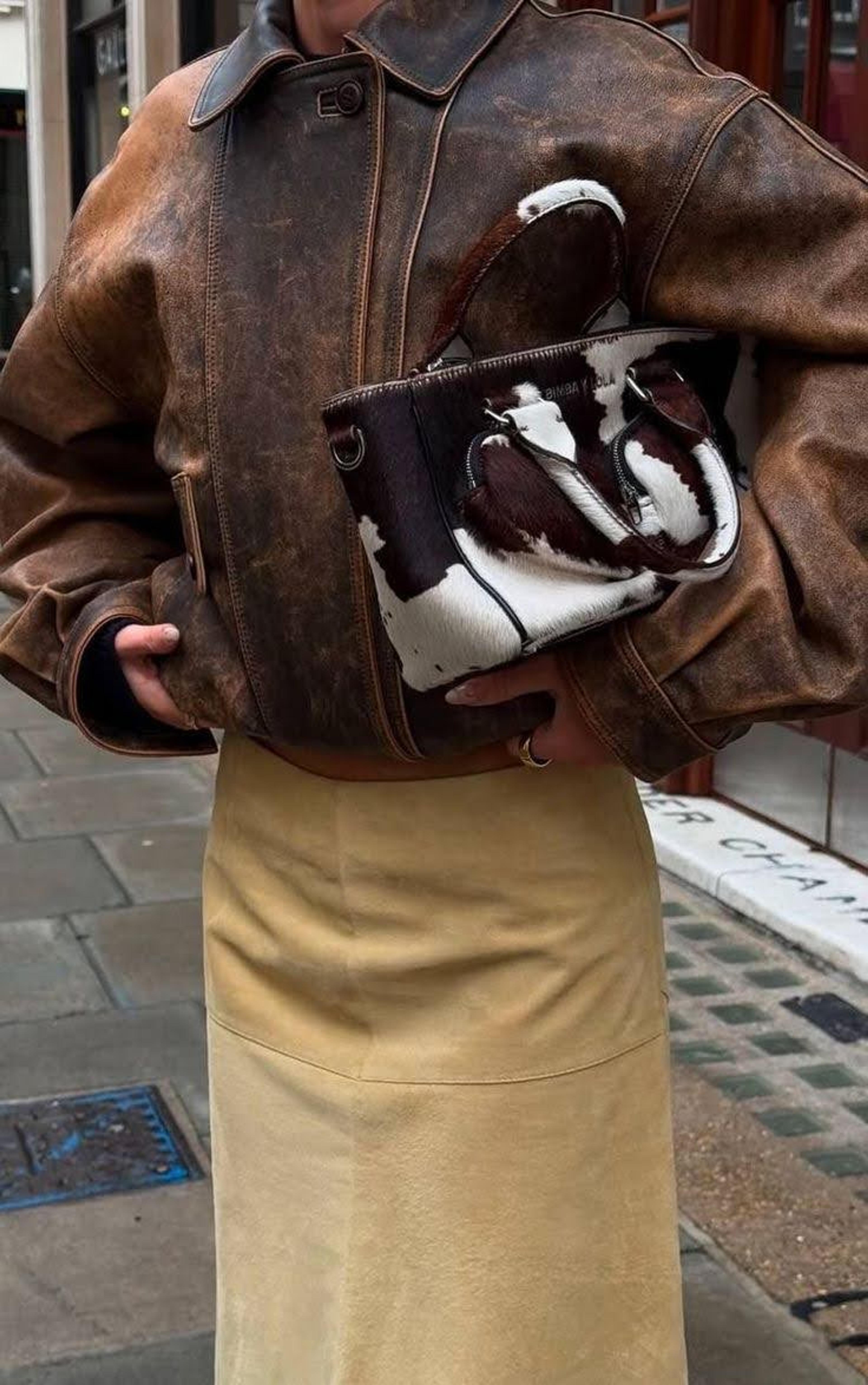A luxury fashion handbag with a cowhide print pattern