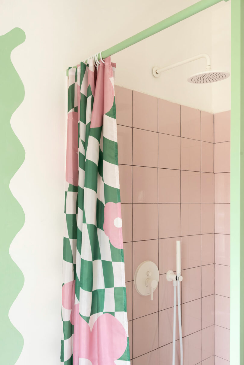 Bright bathroom with pink tiles, green scalloped wall accents, and a floral shower curtain.