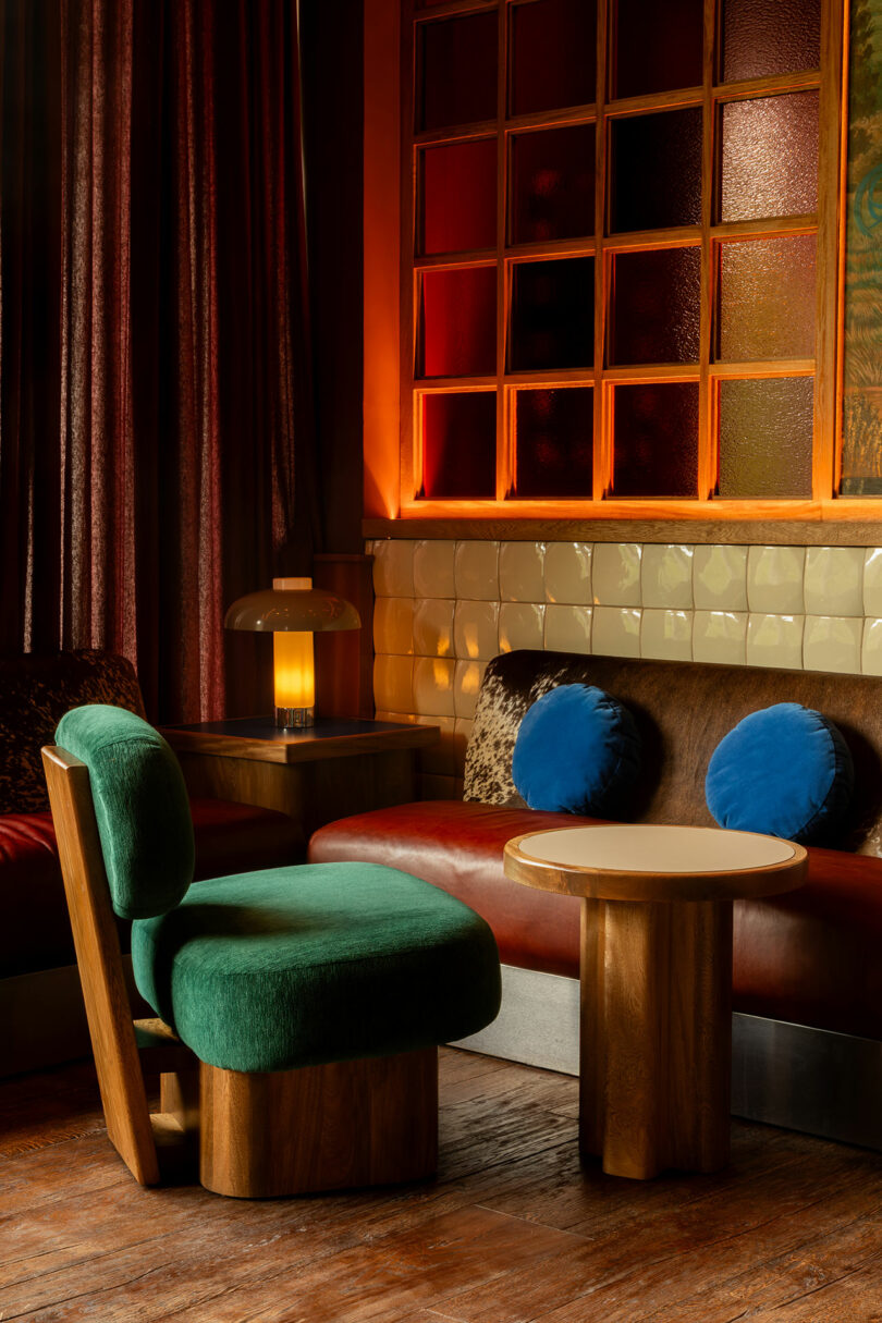 A cozy lounge area with green and blue furniture illuminated by soft, warm ambient light.