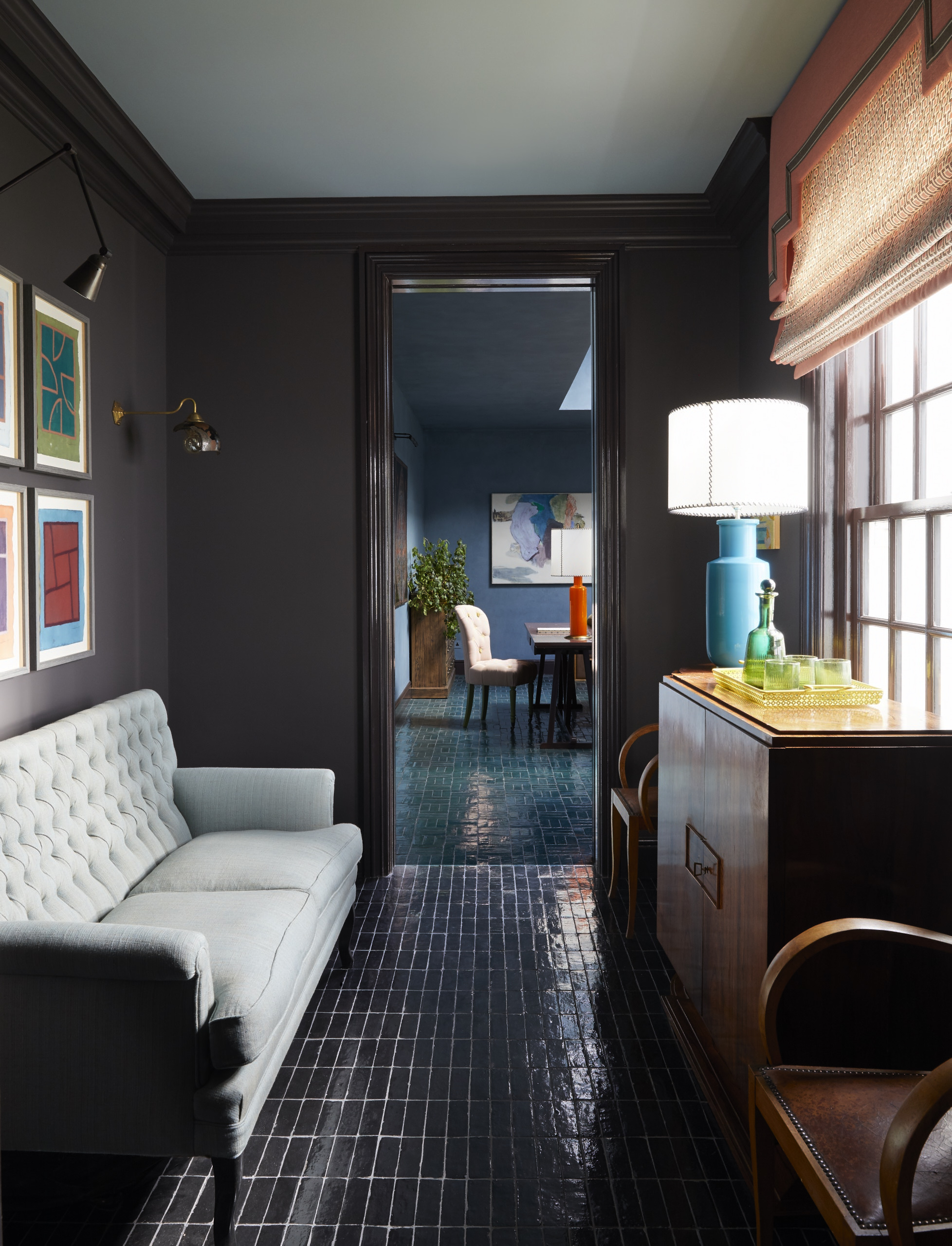 A home bar area with dark brown walls, an Art Deco cabinet, and glossy floor tiles reflecting light.