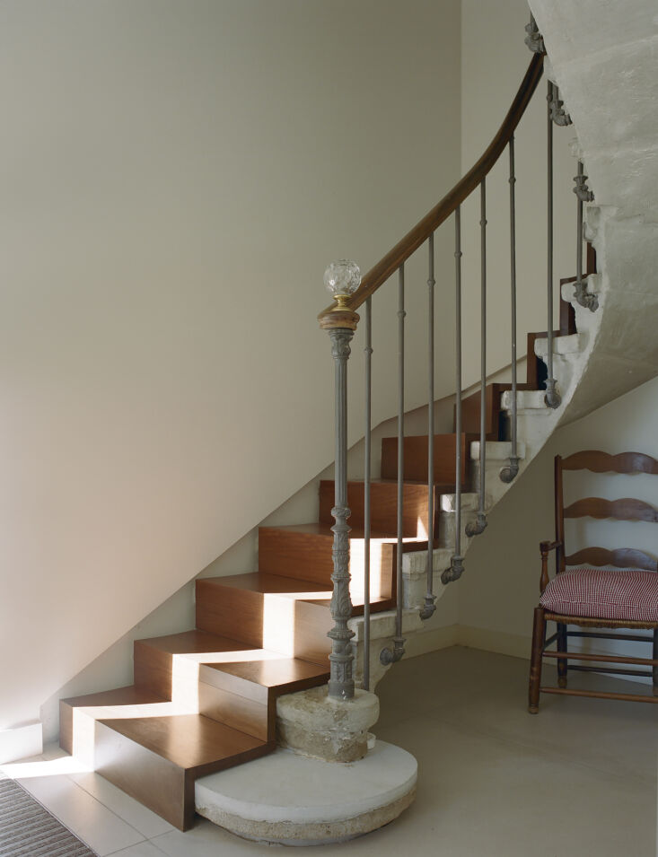 A grand stone staircase featuring a custom-fitted wooden runner that follows the curve of the steps.