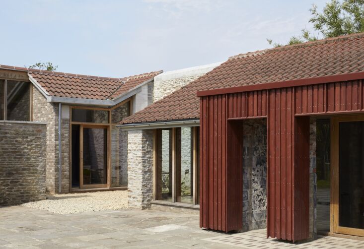 Outdoor courtyard featuring 'brick rugs' made from salvaged materials marking the threshold between the old and new structures.