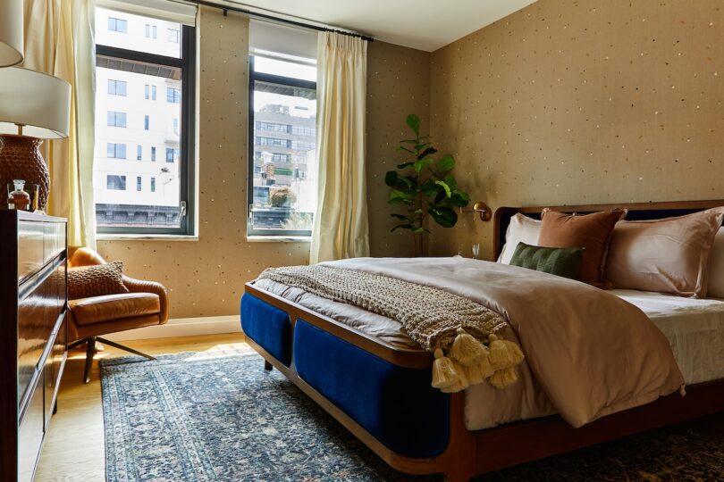 Master bedroom with cream curtains, a patterned rug, a leather chair, and natural light.