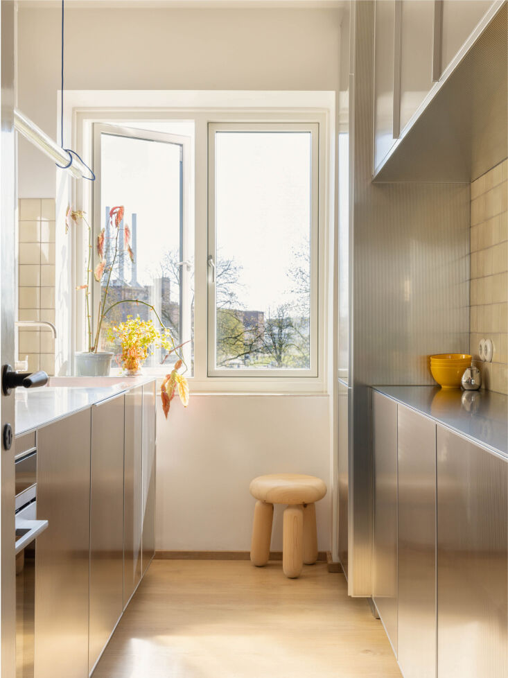 A light-filled kitchen in Copenhagen featuring architectural stainless steel units.