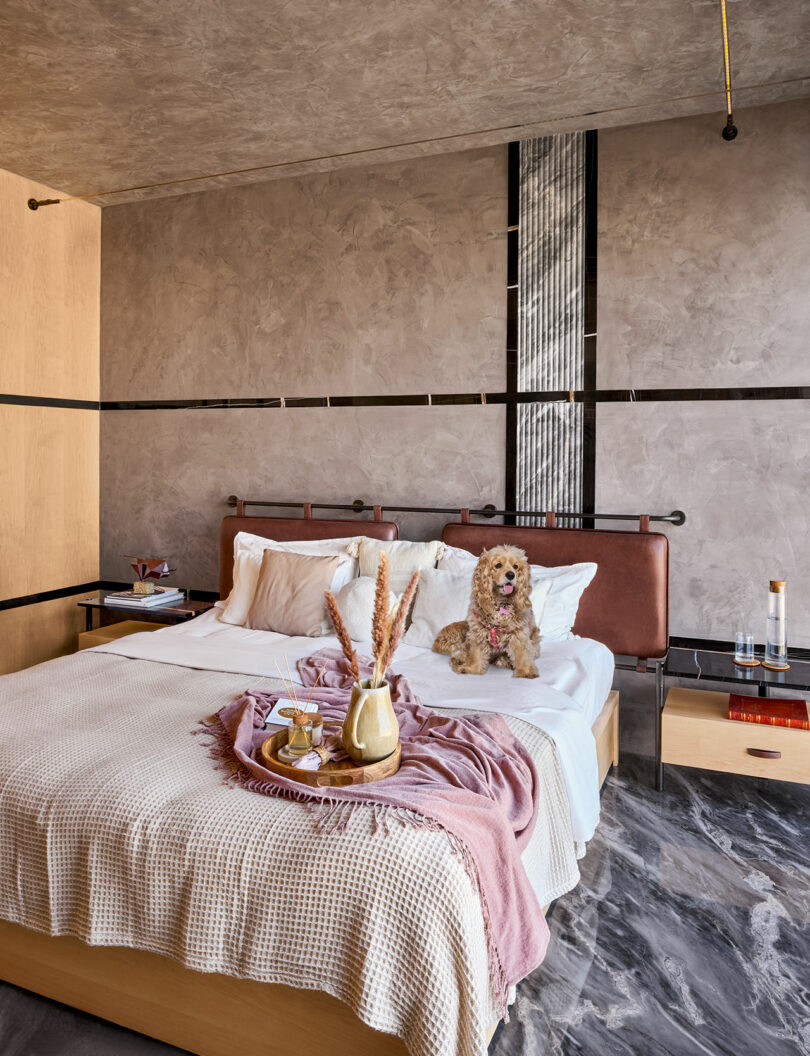 A modern bedroom with textured gray walls, a neutral bed, and natural light.