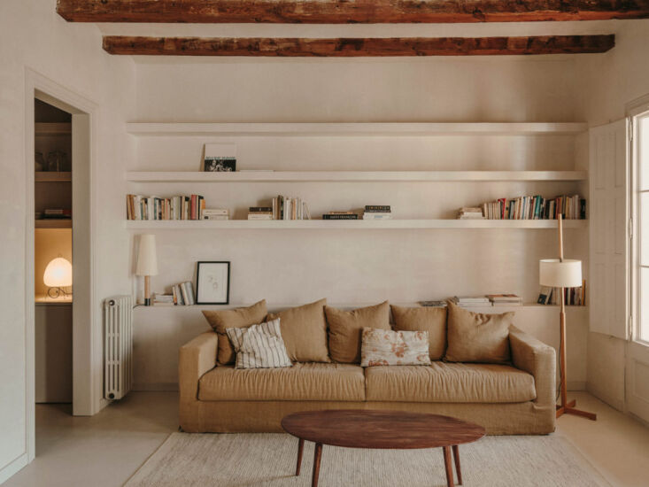 A Básica lamp placed among books on custom built-in wooden shelves in Barcelona.