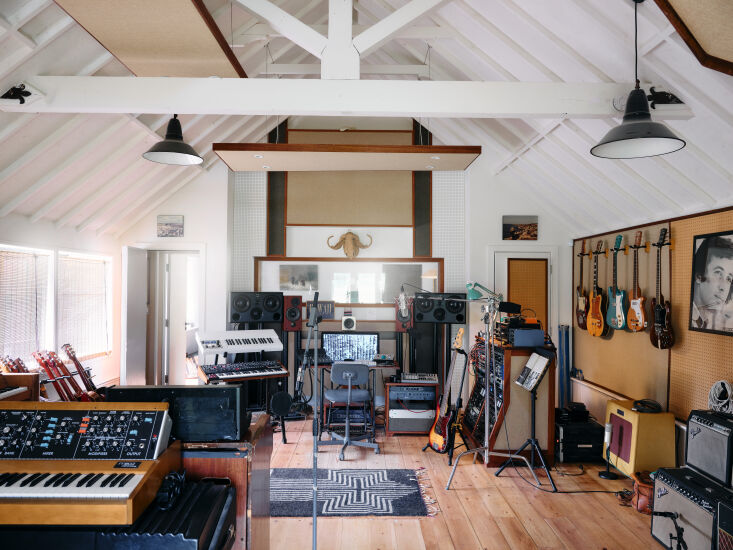 A professional recording studio setup with wood-paneled walls and musical equipment inside a historic building.