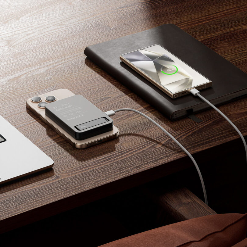 A Kuxiu power bank charging two phones simultaneously using a USB-C cable for the second device.
