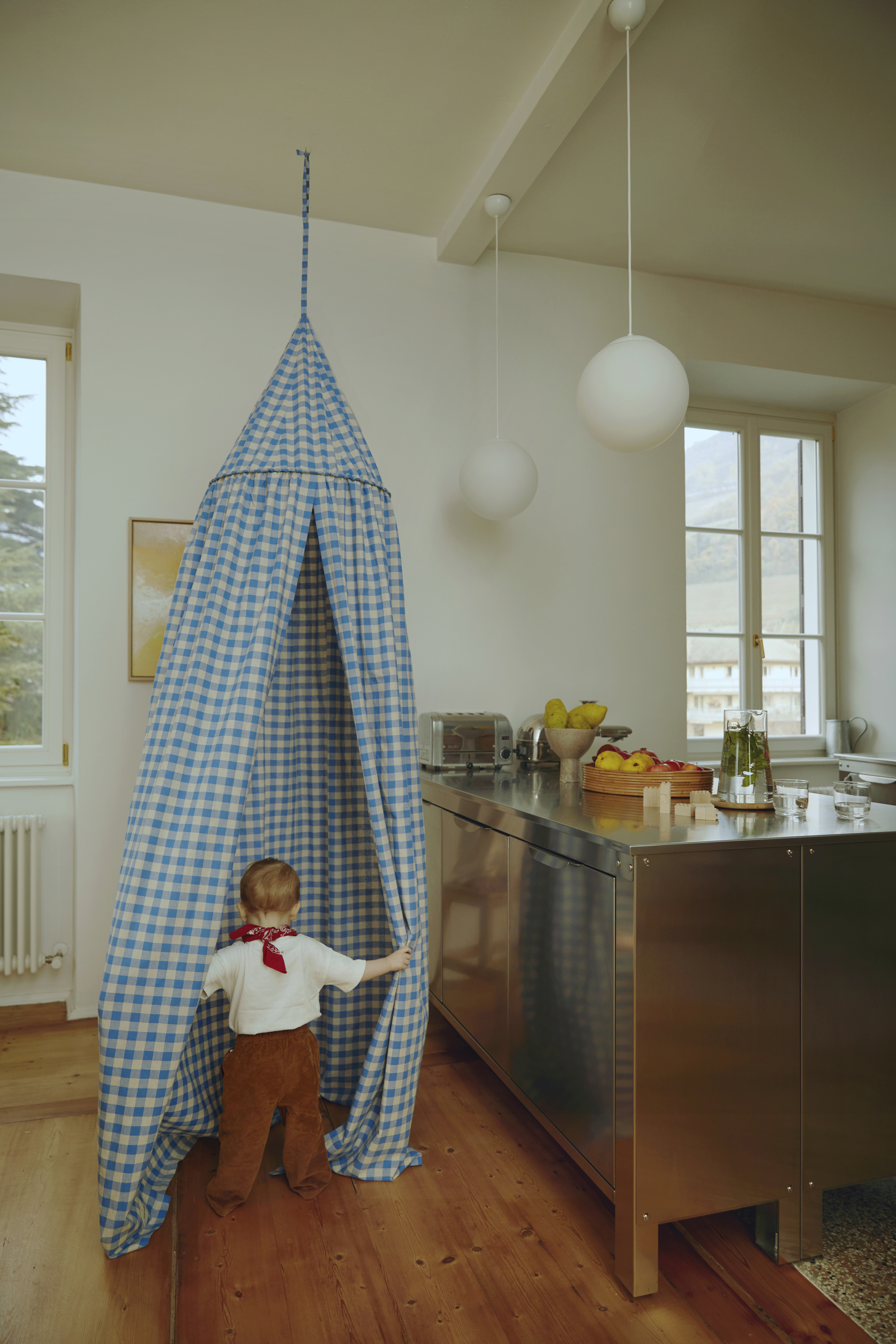 A toddler's bed canopy hanging in a corner near the kitchen to create a designated play zone.