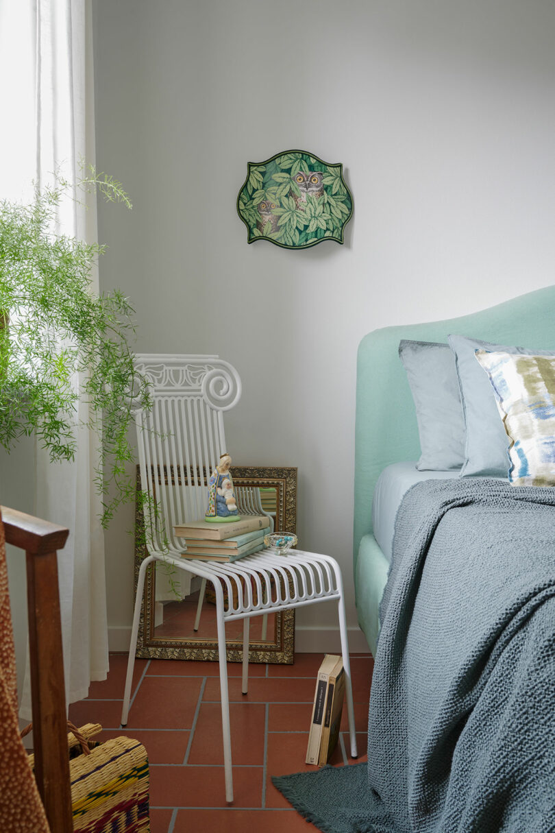 Bedroom with a mint green bed frame, terracotta floor, and owl wall art.
