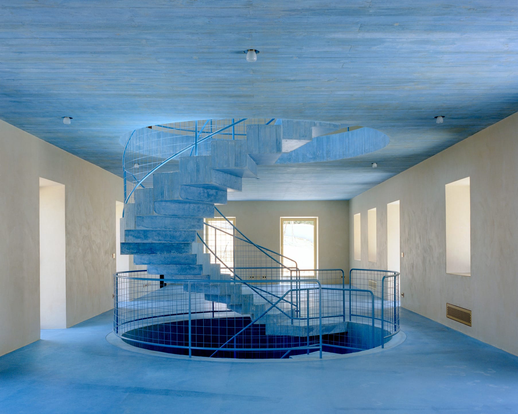 Close-up of the rough stone wall meeting the smooth blue floor in House II.