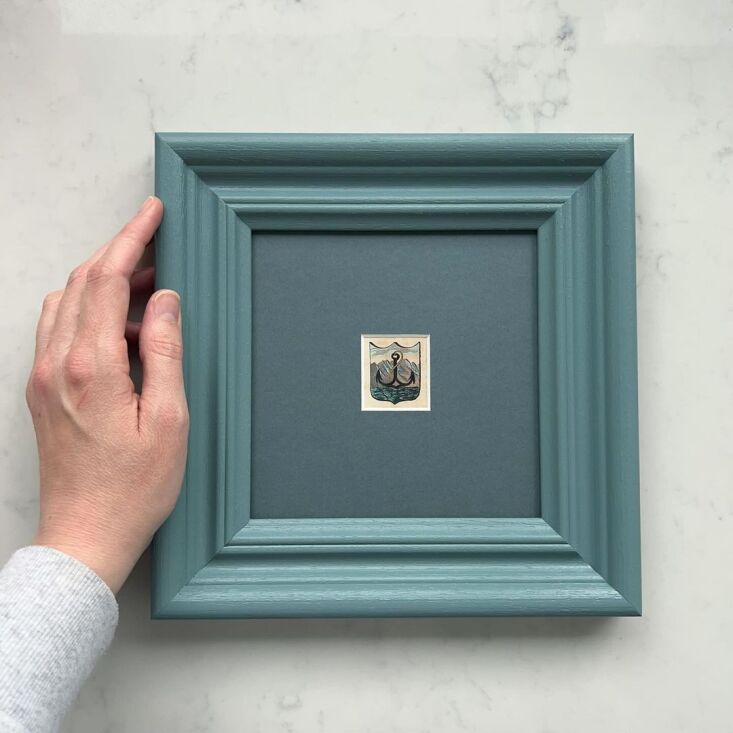 An antique miniature coat of arms artwork set within a deep blue mat and matching blue frame.