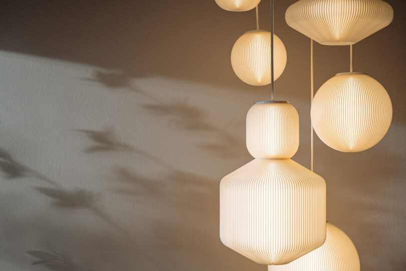 A cluster of white ribbed pendant lights casting soft shadows on a neutral wall.