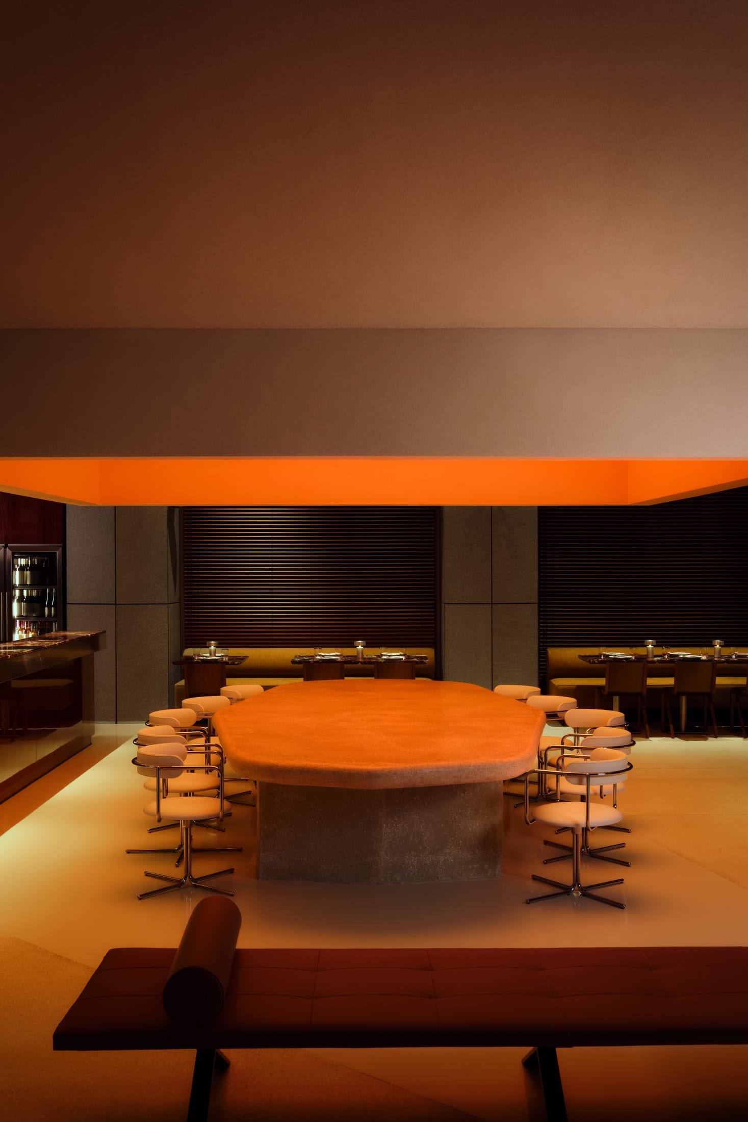 A sleek bar counter made of stainless steel and dark marble against a backdrop of glowing shelves.