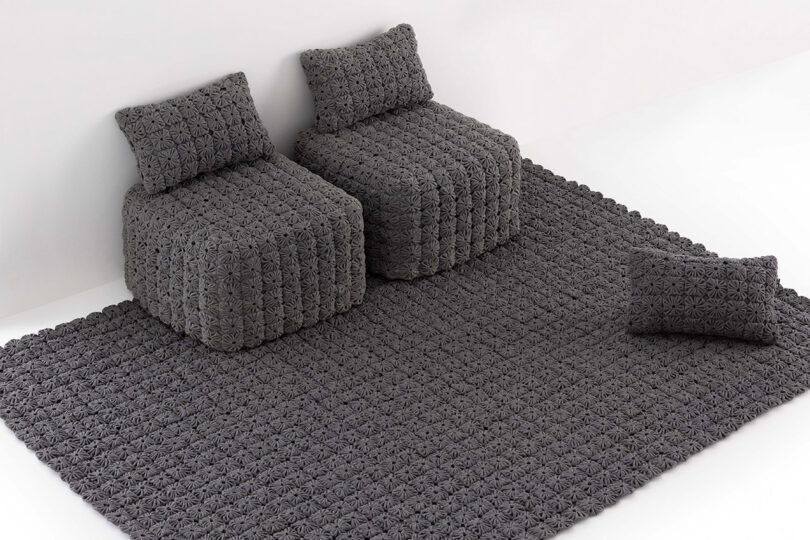 Two textured gray armchairs and a matching rug in a clean, minimalist white room.
