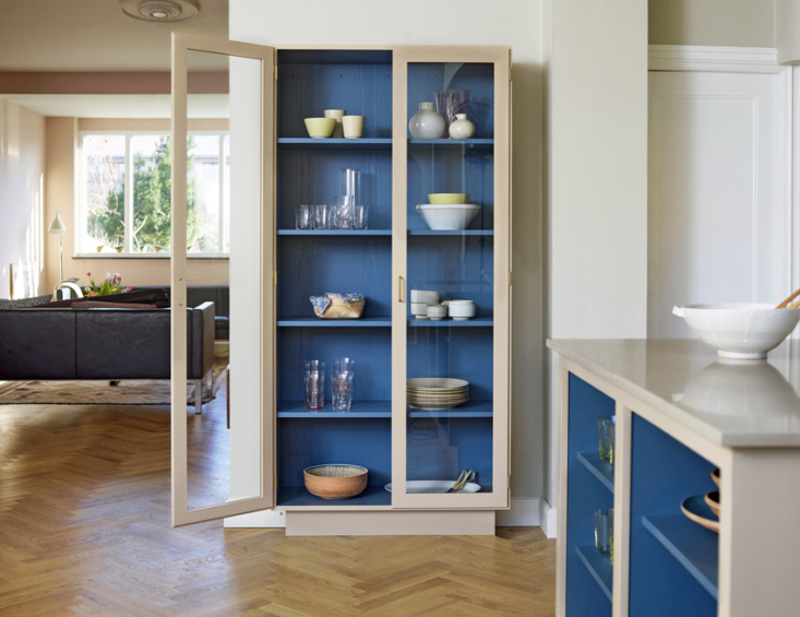 Kitchen cabinet with glass doors showing a vibrant blue interior shelf set against ceramics.