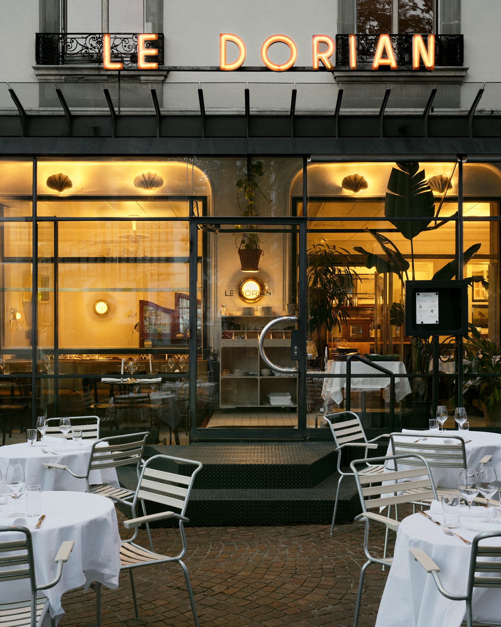 Atmospheric evening view of a table setting at Le Dorian with warm ambient lighting.
