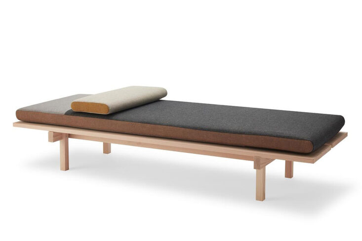 A minimalist Skagerak Reykjavik Daybed with grey Re-wool upholstery against a wood-paneled wall.