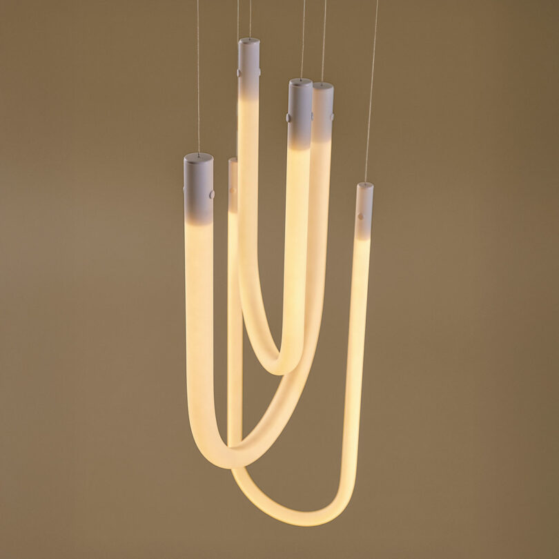 A modern smart pendant light with four curved glowing tubes hanging from a ceiling.