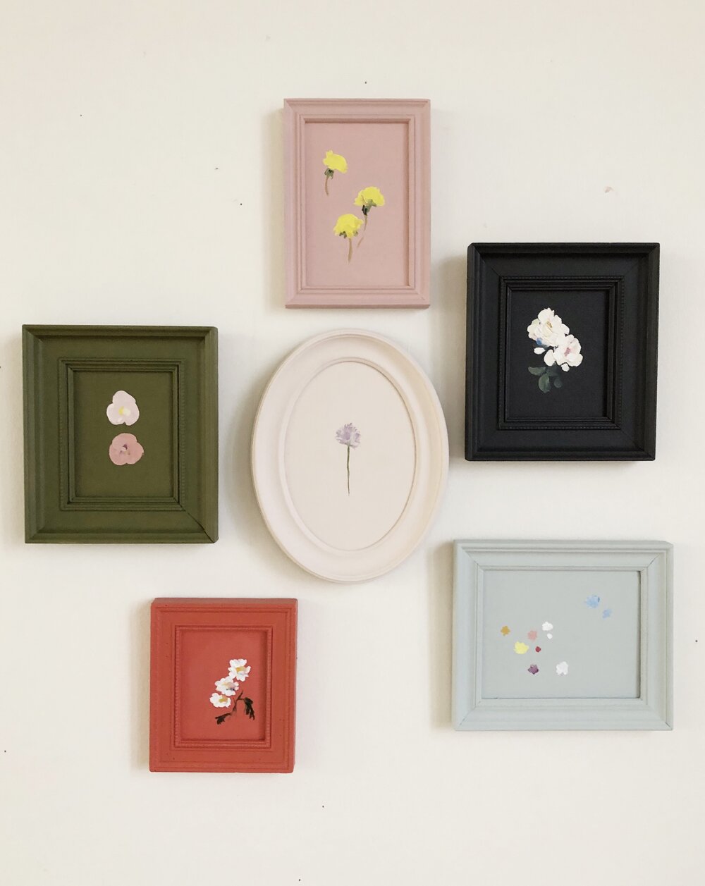 A group of upcycled frames in various sizes and shapes, each painted in a single solid matte color.